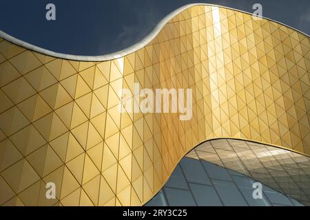 Modern building made of glass and metal. Golden color in architecture of building. Modern style of building. Mirror surface in palace. Stock Photo