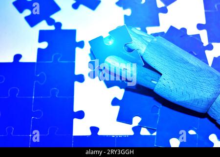 Robot hand holding a jigsaw puzzle . Stock Photo