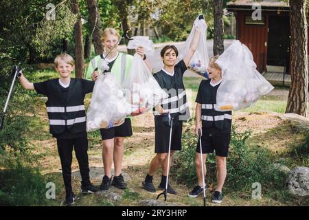 Full length portrait of smiling male volunteers holding garbage bags Stock Photo