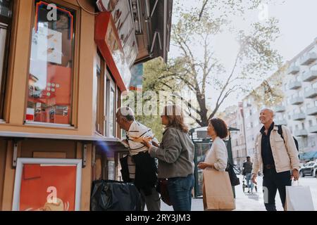 Male and female senior friends buying desert from ice cream shop at street Stock Photo