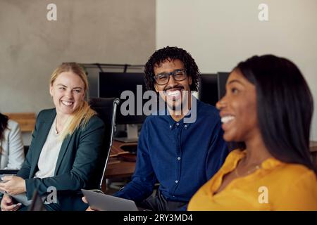 Happy multiracial colleagues sitting together at office Stock Photo
