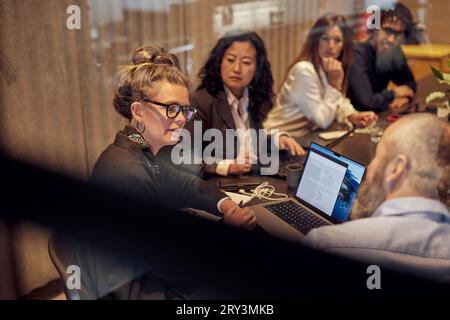 Businesswoman discussing with businessman by colleagues in board room Stock Photo
