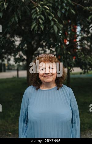 Portrait of smiling senior woman standing at park Stock Photo