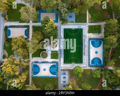 Sport courts at a park in aerial view. Aerial photo about foutball, basketball courts and ping pong tables. Birds eye view about a Recreation park. Stock Photo