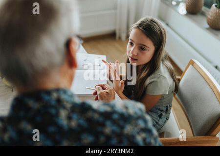 Girl doing homework with grandfather at home Stock Photo