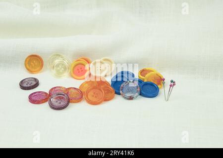 Multicolored buttons, with a needle and threads, on a fabric background. Close-up. Background with copy space Stock Photo