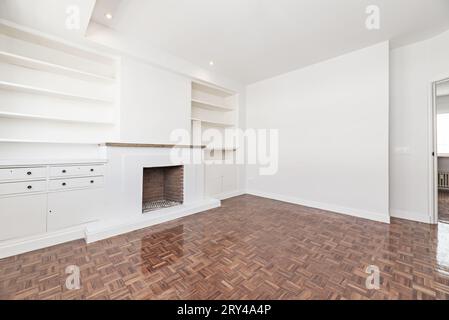 Living room in apartment with built-in fireplace, bright reddish parquet floors, halogen spotlights Stock Photo