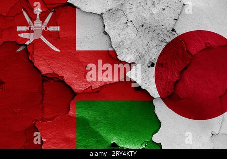 flags of Oman and Japan painted on cracked wall Stock Photo