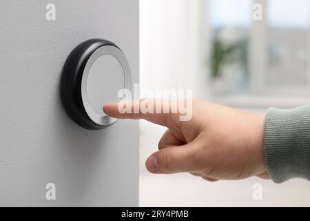Man adjusting thermostat on white wall indoors, closeup. Smart home system Stock Photo