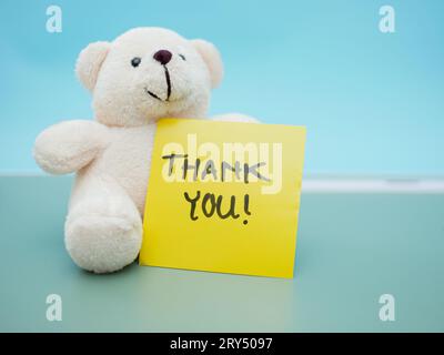 words thank you written on a sticky note with a white teddy bear beside it Stock Photo