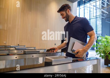 Happy successful businessman or entrepreneur enters office going through security gates doorway Stock Photo