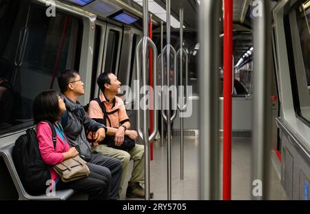 Passengers travelling on the airport rail link, looking up at the information board. Stock Photo