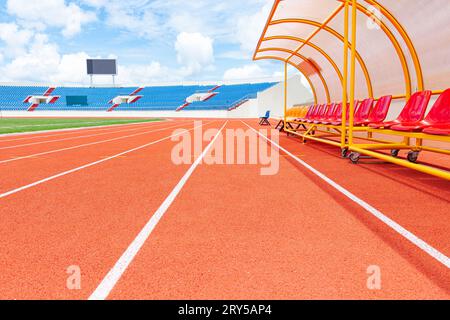 Da Lat city, Vietnam, July 5 2023:  Red reserve chair bench for staff, coach, substitutes players bench in outdoors sport stadium on sunny cloud day Stock Photo