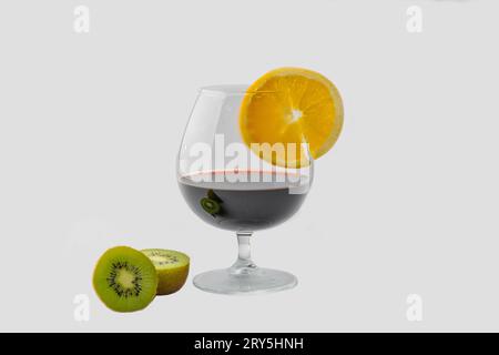 A captivating image featuring a chilled wine glass filled with velvety red wine, adorned with half-cut kiwi pieces and orange sliced garnish. It stand Stock Photo