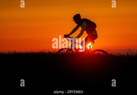 Unlingen, Germany. 29th Sep, 2023. A cyclist is riding in the morning backlit by the rising sun. Credit: Thomas Warnack/dpa/Alamy Live News Stock Photo