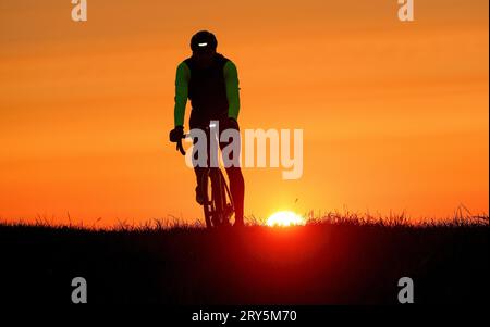 Unlingen, Germany. 29th Sep, 2023. A cyclist is riding in the morning backlit by the rising sun. Credit: Thomas Warnack/dpa/Alamy Live News Stock Photo