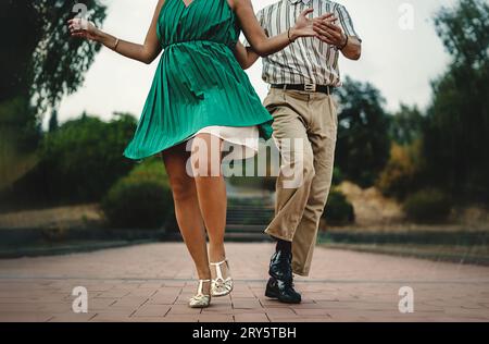 Close-up of a couple's feet and attire while performing swing dance moves outdoors. Authentic swing shoes and clothing details. Stock Photo