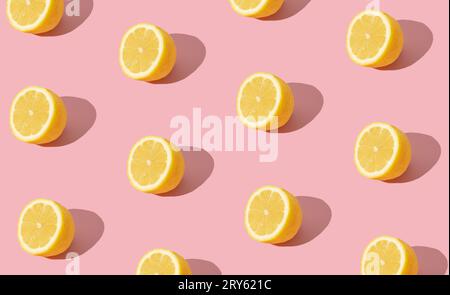 Trendy sunlight summer fruit pattern made with yellow lemon slice on bright light pink background. Minimal summer concept. Creative food idea. Stock Photo