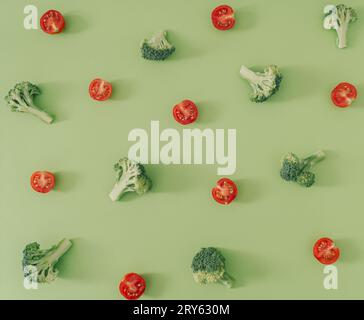 Trendy food pattern made of broccoli and cherry tomatoes on pastel green background. Creative vegetable pattern idea. Flat lay broccoli. Stock Photo