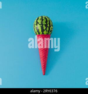 Ice cream made of pink waffle ice cream cone and scoop of watermelon fruit on light blue background. Summer ice cream composition. Minimal concept. Stock Photo