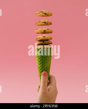 Green waffle ice cream cone with chocolate cookies on bright pink background. Minimal food concept. Summer creative idea. Yummy chocolate cookie chip. Stock Photo