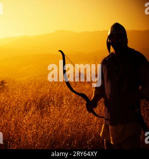 Silhouette of a man dressed as a warrior holding a bow. California, United States Stock Photo