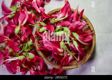 Fresh red vegetable humming bird flower  in wicker basket on table Stock Photo