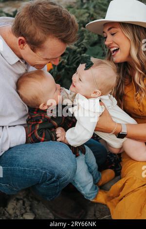 Family fun in pumpkin patch, laughter fills air.' Stock Photo