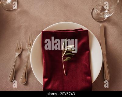 Elegant holiday table setting with a white plate, red napkin, an Stock Photo
