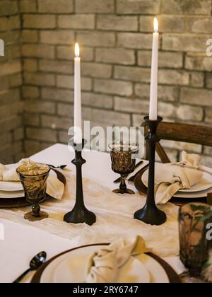 Cozy autumn table setup, lit candles, wood accents, vintage glas Stock Photo