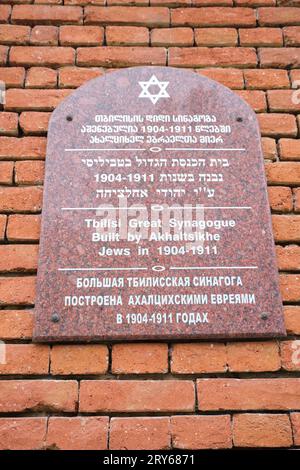A marble plaque, mounted on the wall, detailing the building of the temple in 1904-1911. At the red brick Grand Jewish Synagogue in Tbilisi, Georgia, Stock Photo