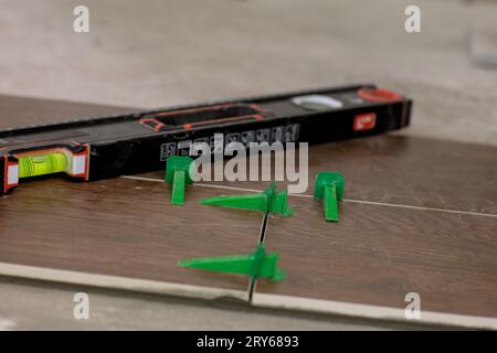 Tile levelling system, four plastic green clips with wedges. Close-up view, selective focus, blurred background. Stock Photo