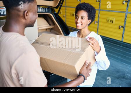 Guy and his girlfriend are unloading boxes of things from a car Stock Photo