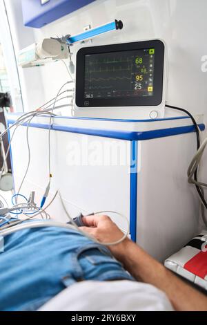 Man in casual clothes is connected to a cardiograph in an ambulance Stock Photo