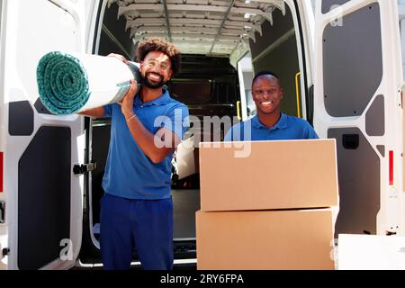 Movers Doing Furniture And Carpet Removal From Truck Or Van Stock Photo