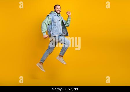 Full length size photo body cadre of running shopaholic guy spring time sale season promo denim apparel isolated on yellow color background Stock Photo