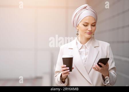 Muslim woman with coffee in hand enjoys break surfing internet Stock Photo
