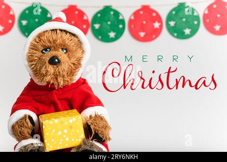 Funny teddy bear in Santa Claus suit with Christmas present Stock Photo