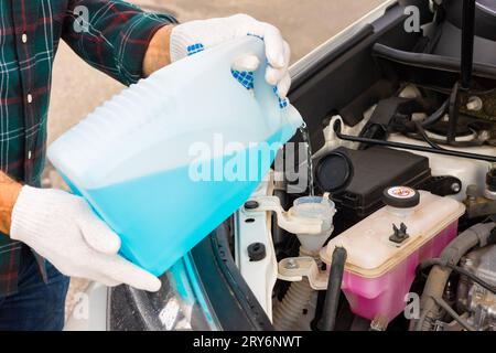 pour antifreeze. the driver pours fluid into the washer reservoir. washer  fluid. glass cleaner. man pouring windshield wiper into car. driver pours  an Stock Photo - Alamy