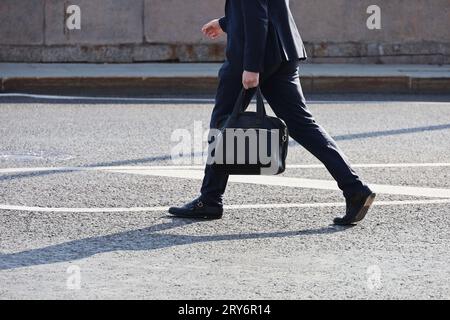 Man in a business suit walking down the street with briefcase in hand Stock Photo