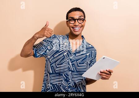 Photo portrait of attractive young man hold tablet working remotely wear trendy blue print clothes isolated on beige color background Stock Photo