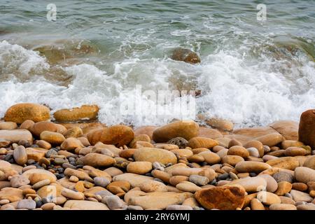 Hopeman Moray Coast Scotland white surf breaking on coloured sandstone rocks and pebbles Stock Photo