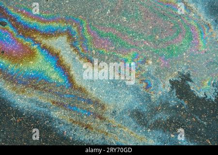 Colored oil stains close up, the color of the gasoline stain on the pavement road as a texture or background. Stock Photo