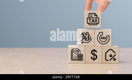 income tax return and submit for payment tax documents. Hand putting tax icon on wooden cube. taxes paid by individuals and corporations such as VAT, Stock Photo