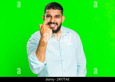 Knock-knock who is there. Confused excited Indian man knocking door gesture asking who is at home, feeling embarrassed, no idea, being clueless and uncertain. Guy isolated on chroma key background Stock Photo