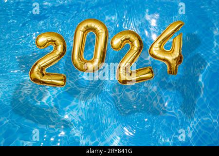 2024 Inflatable golden numbers on water ripples surface, happy new year with a swimming pool concept Stock Photo