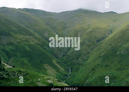 Running waterfall on a cloudy valley in Vall de Nuria Stock Photo