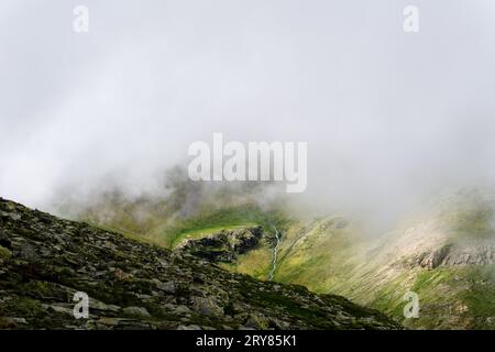 Running waterfall on a cloudy valley in Vall de Nuria Stock Photo