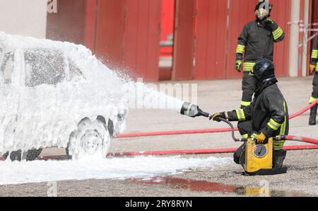 firefighters putting out the car fire after the terrible road accident with dense white foam Stock Photo