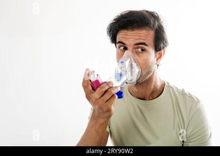 Asian young man from india using a respiratory inhaler. Study shot on white background, selective focus. Stock Photo